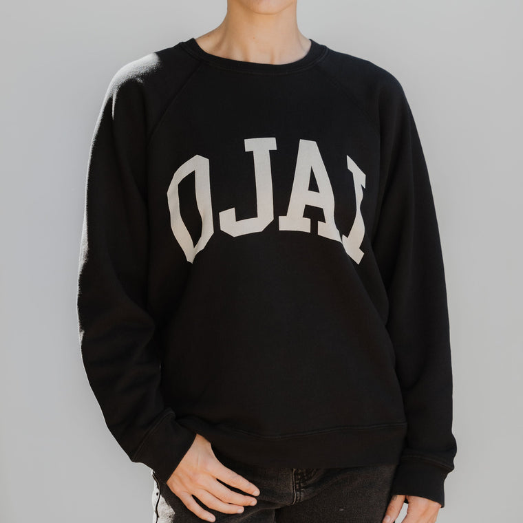 Person wearing a black sweatshirt with 'OJAI' text on a gray background