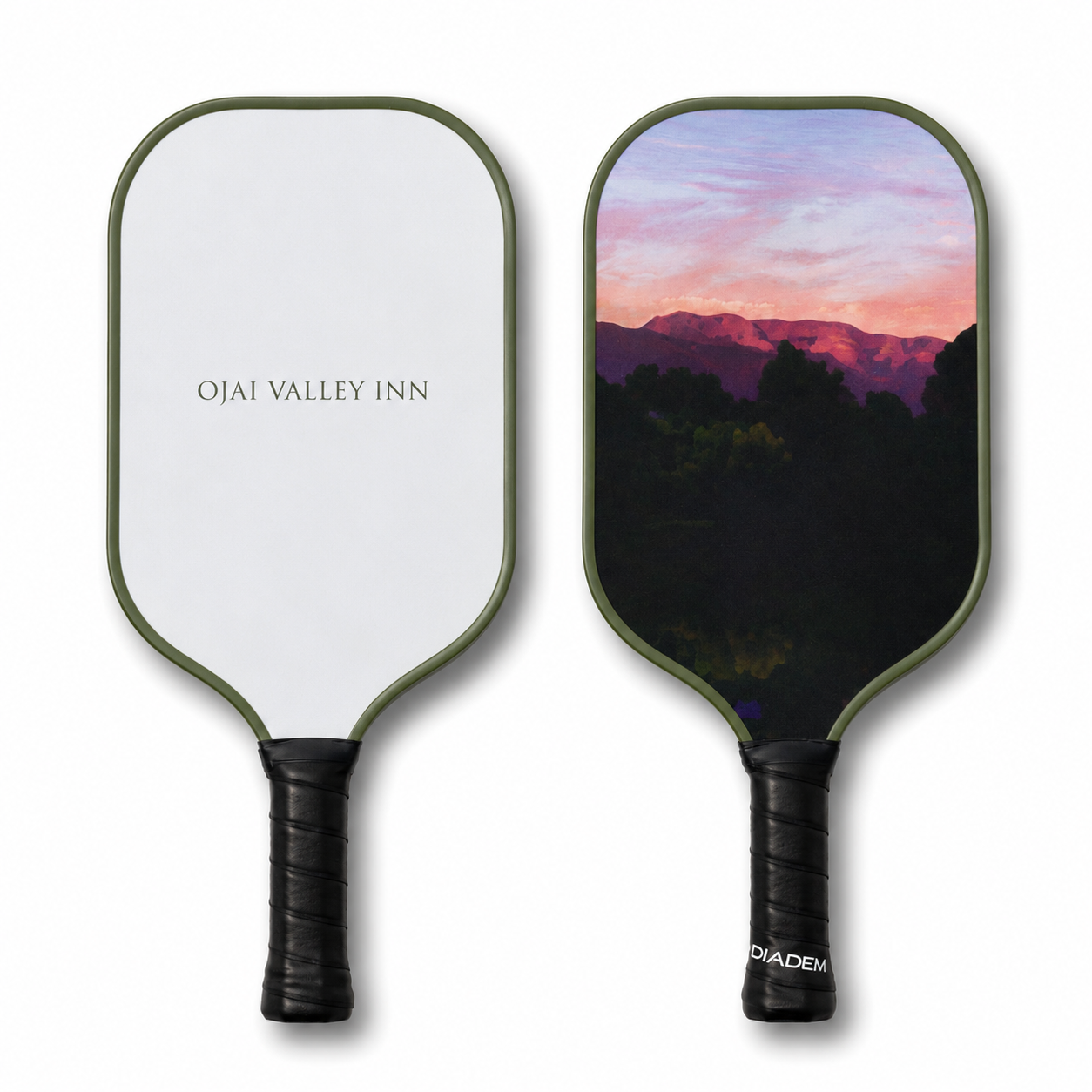 Two pickleball paddles shown side by side on a white background. The left paddle is white with the text 'OJAI VALLEY INN' and an olive green edge.