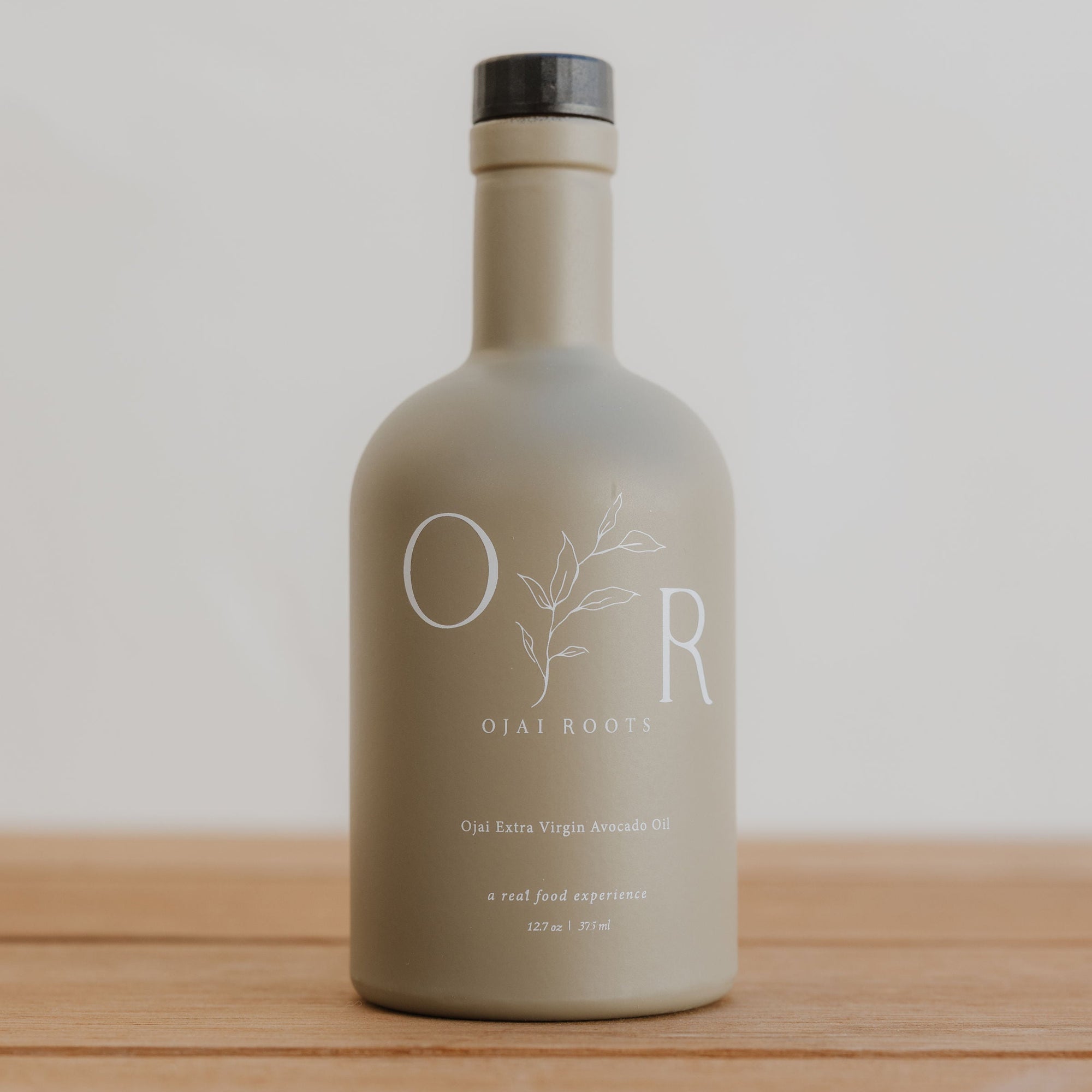 Bottle of OR olive oil on a wooden surface with a plain background