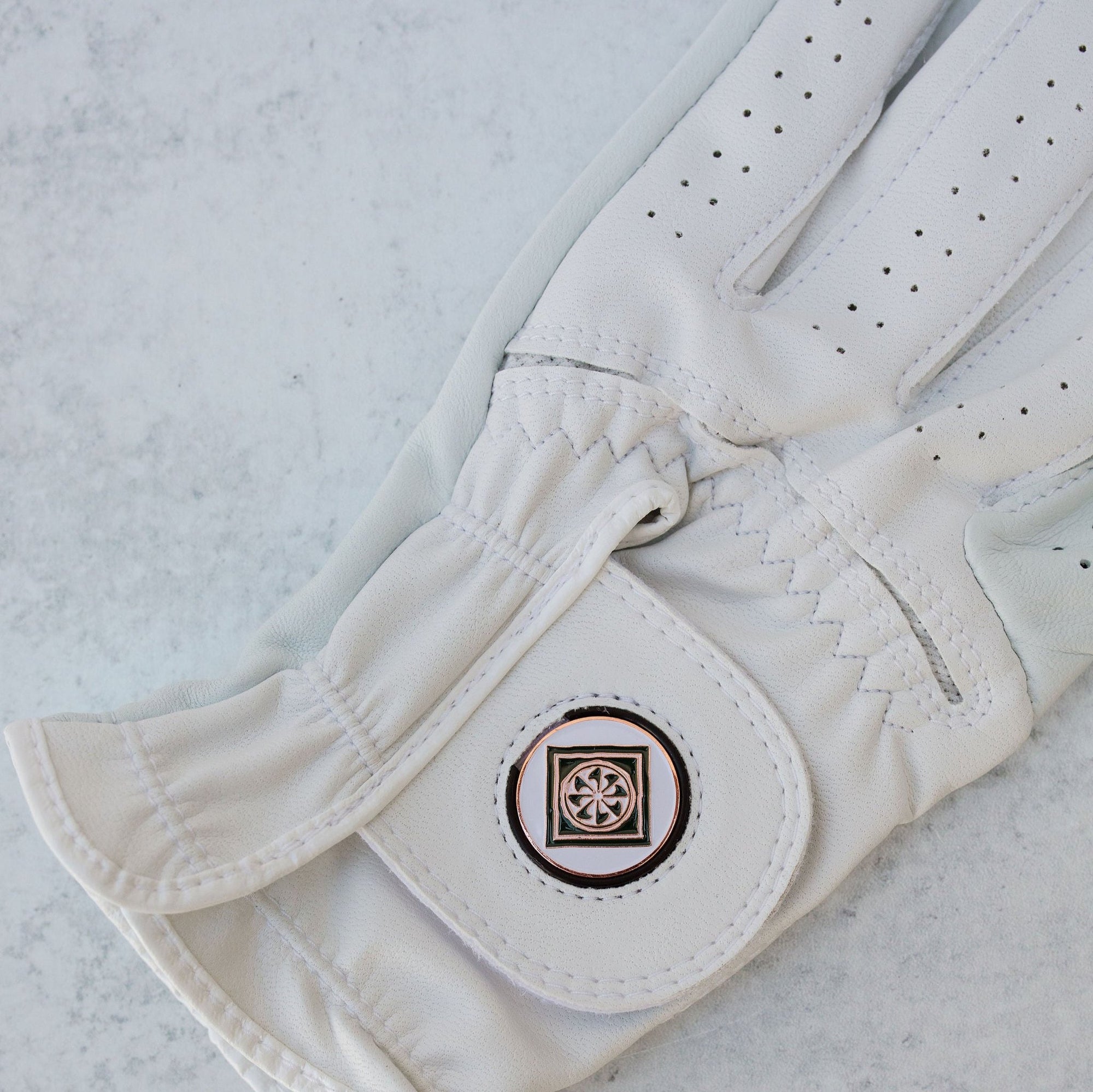 A white golf glove with the Ojai Valley Inn logo on it, placed on a marble surface.
