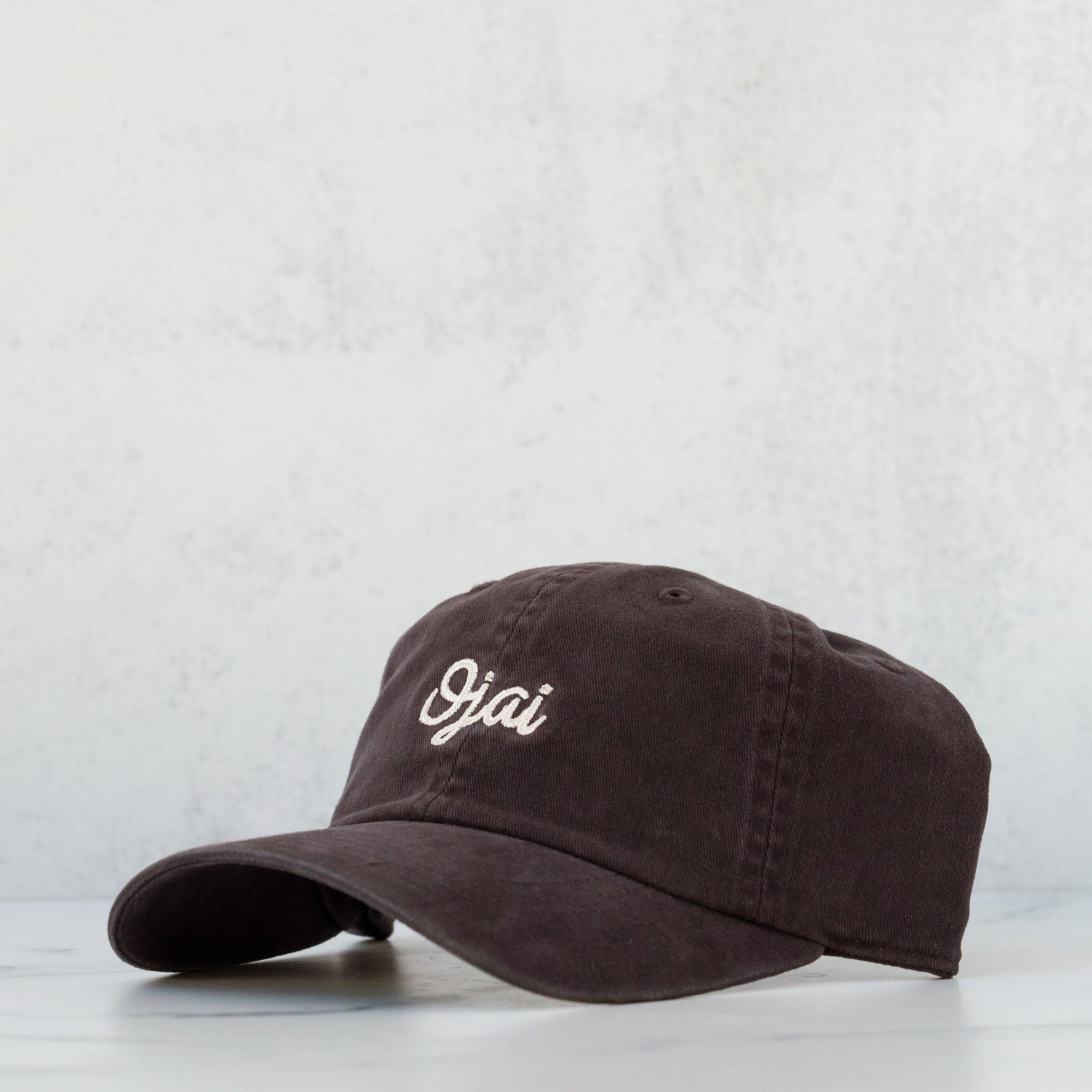 A navy-colored, cotton slouch hat with a curved brim and the 'Ojai' brand name printed on the front.