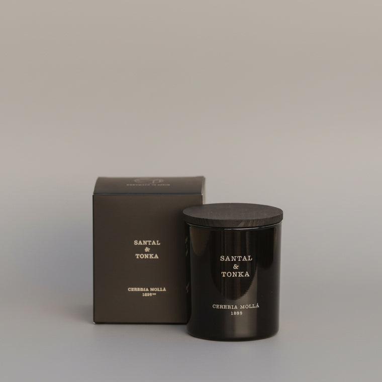 Black candle and box labeled 'Santal & Tonka' on a marble surface with a marble background