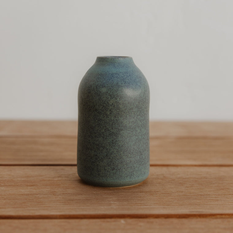 Blue ceramic vase on a wooden surface with a plain background