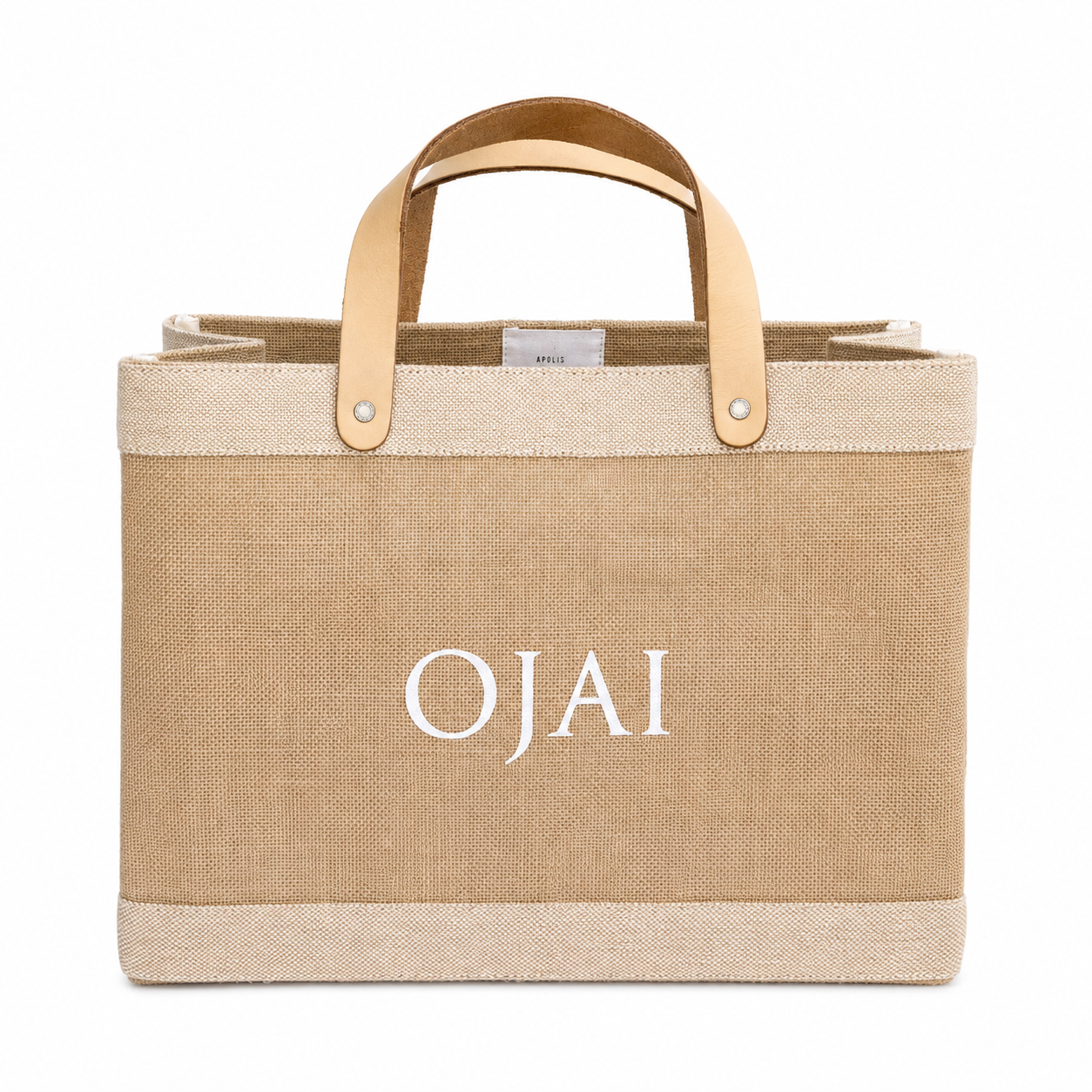 A natural jute tote bag with light tan leather handles and the brand name 'OJAI' printed in white serif letters on the front, set against a plain white background.