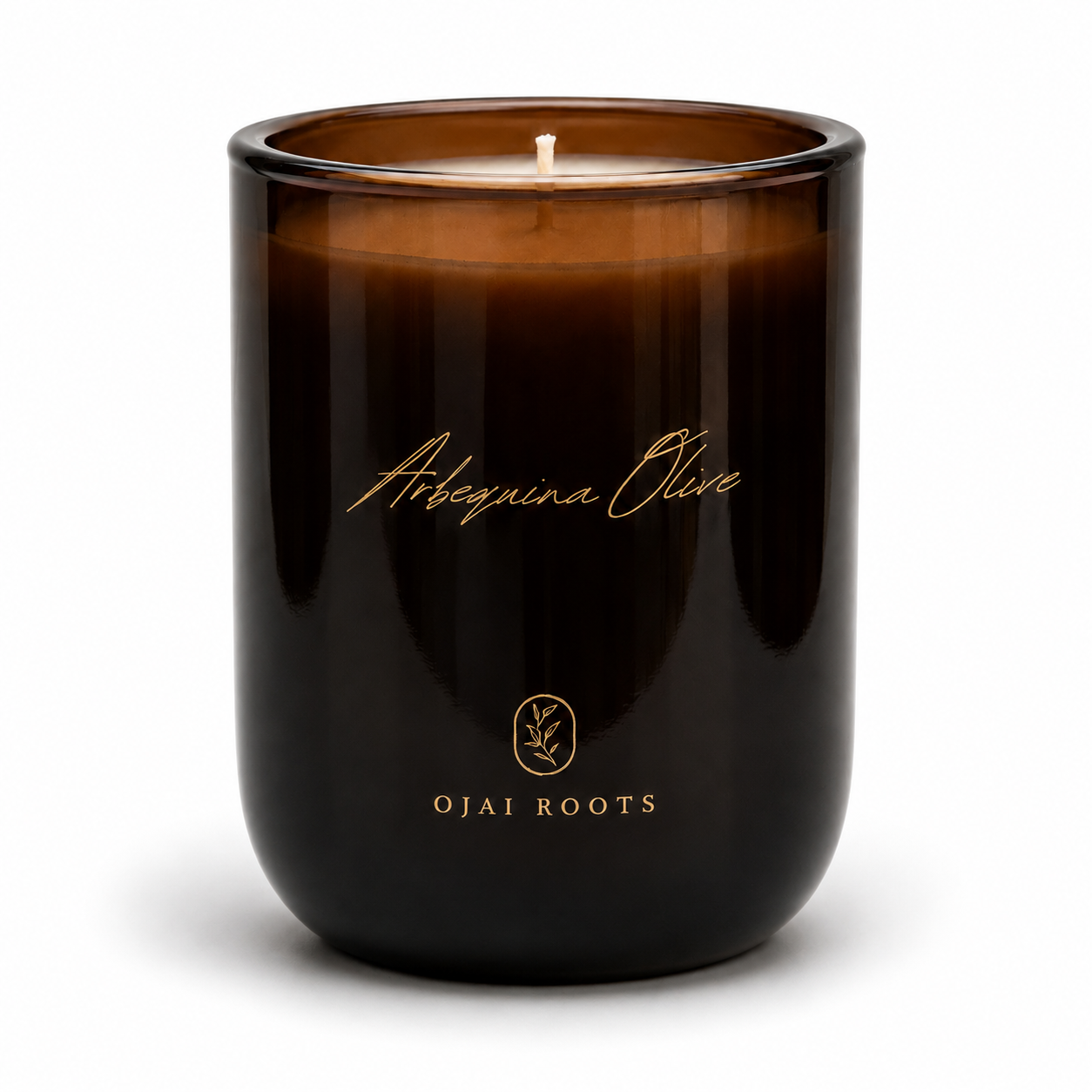 An amber glass jar candle with a single wick, featuring gold foil text that reads 'Arbutoria Olive' and 'OJAI ROOTS' on a clean white background.