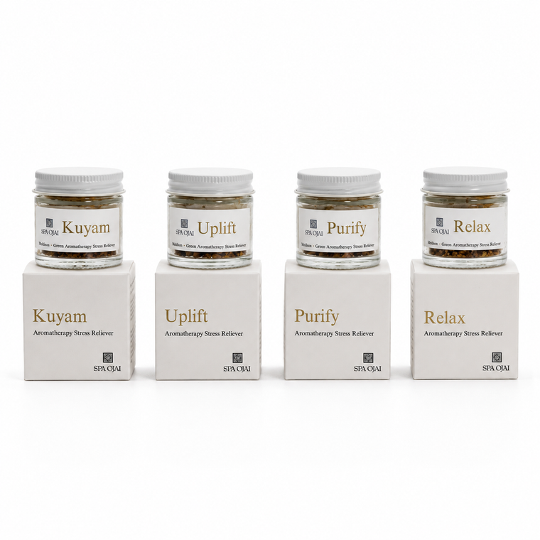 Four small glass jars of spa ojai aromatherapy stone salves with white lids, displayed on top of their matching white cardboard boxes.