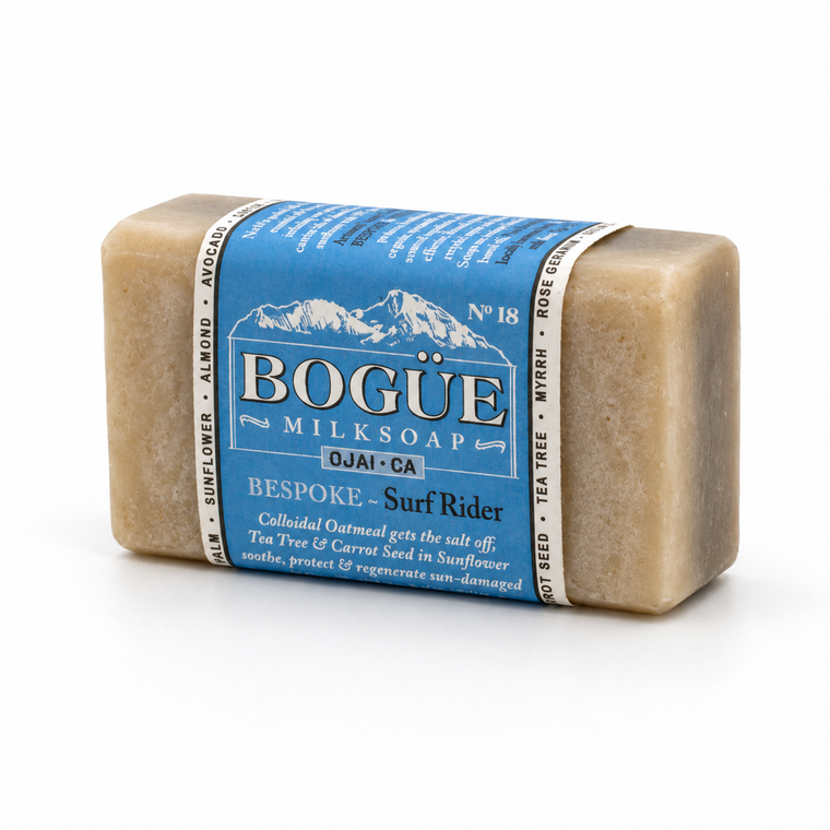 A rectangular bar of BOGÜE Milksoap labeled 'Bespoke - Surf Rider' in natural beige soap with a blue paper label, photographed on a clean white background.