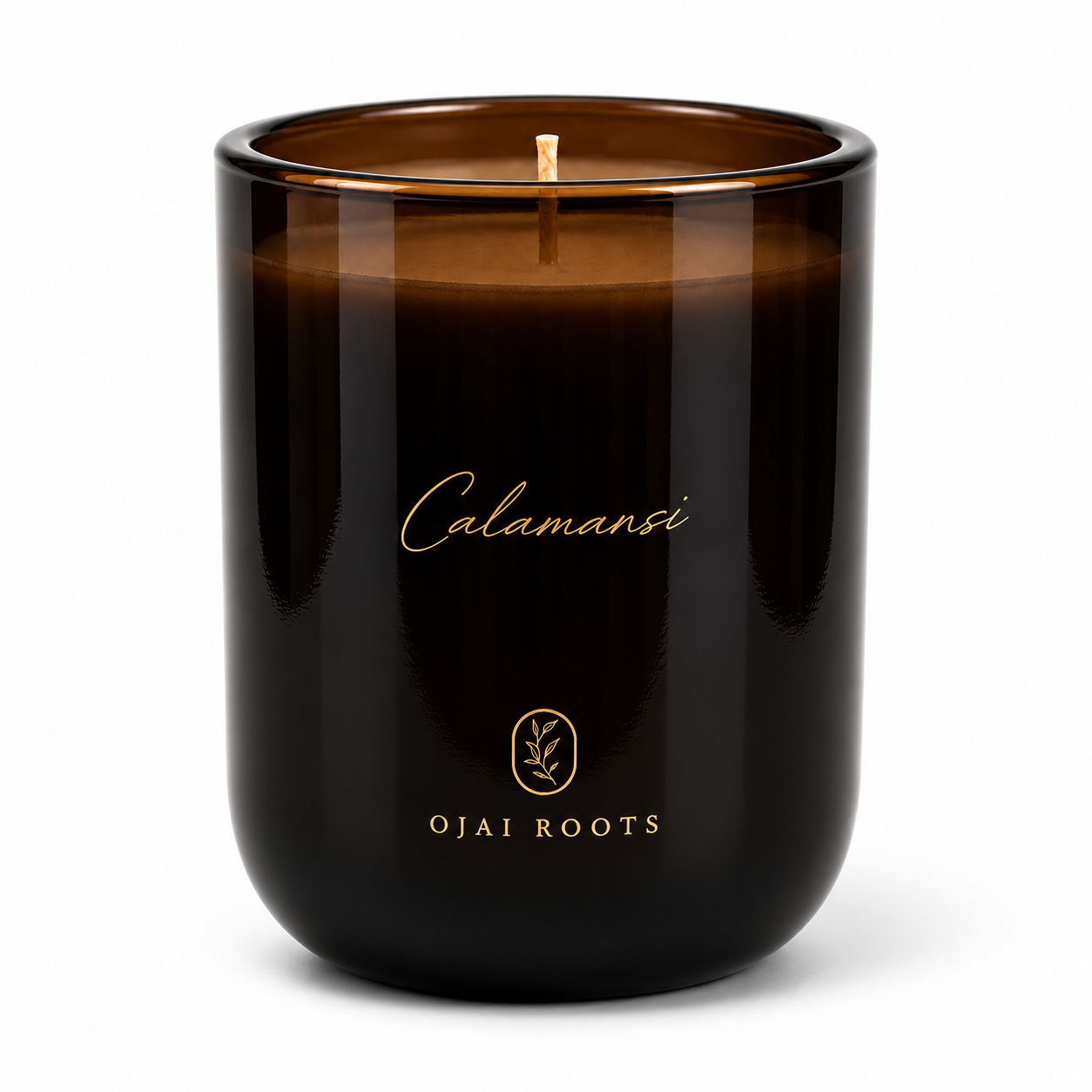 An amber glass jar candle with a single wick, featuring gold foil branding that reads 'Calamansi' and 'OJAI ROOTS' on a clean white background.
