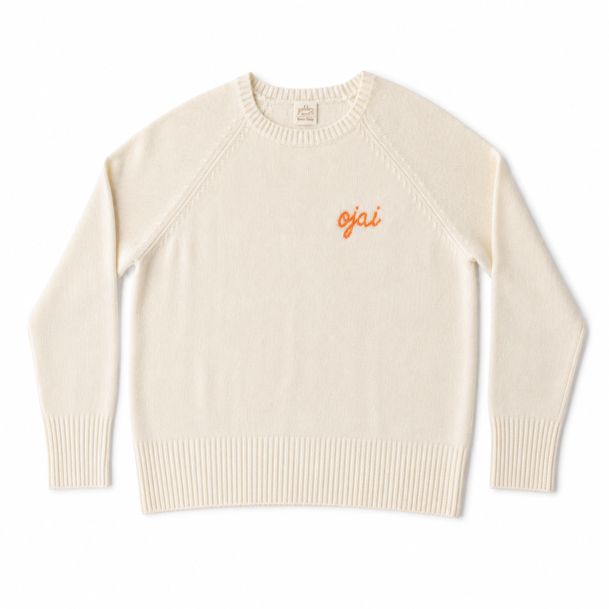 A cream-colored knit crewneck sweater with 'ojai' embroidered in orange on the left chest, displayed flat against a white background.