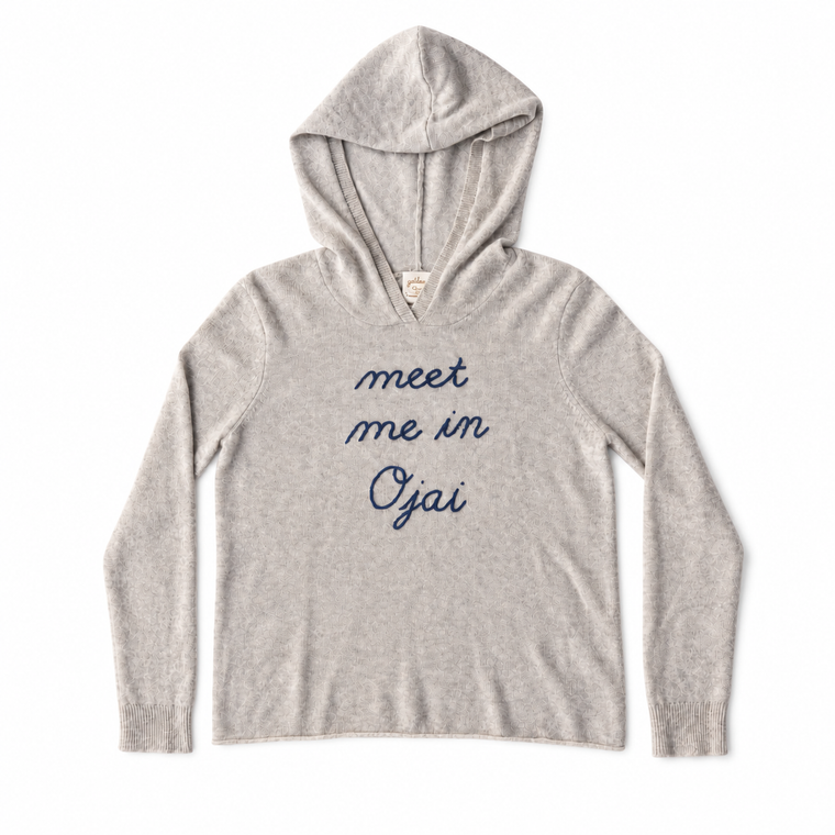 A light heather gray hooded sweatshirt with the phrase 'meet me in Oyai' printed in navy blue script across the chest, displayed flat against a white background.