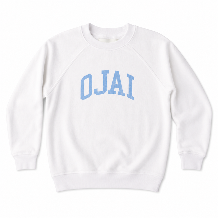 A white crewneck sweatshirt with 'OJAI' printed in light blue varsity block letters across the chest, displayed flat against a white background.