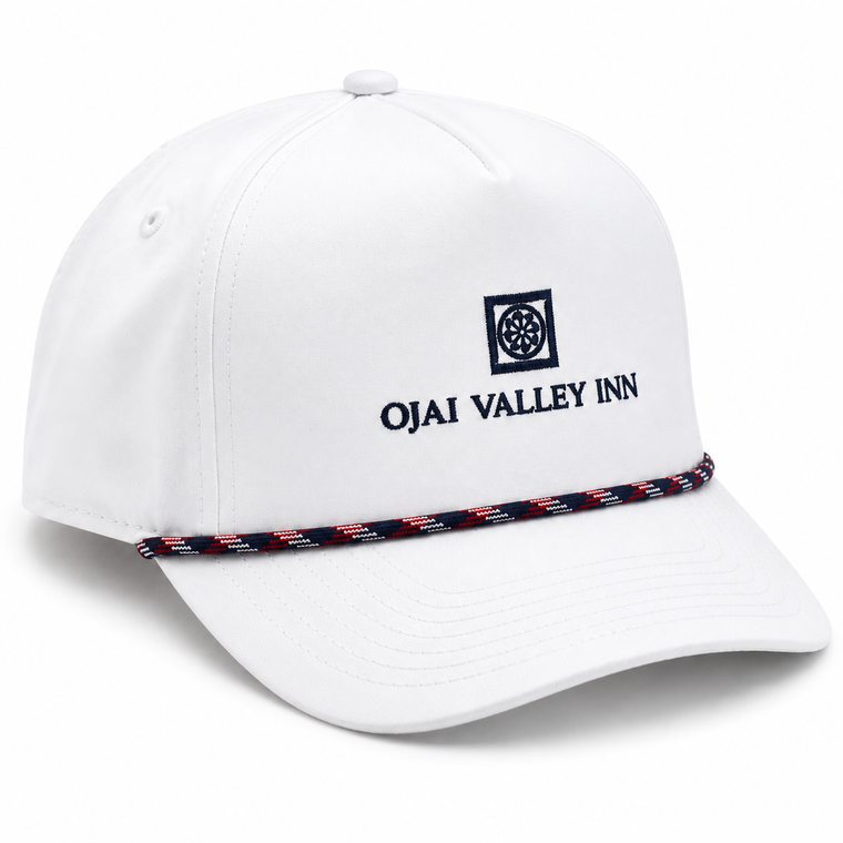 A white baseball cap featuring the text 'OJAI VALLEY INN' and a square logo embroidered in navy on the front, with a thin navy, red, and white patterned rope detail across the brim.