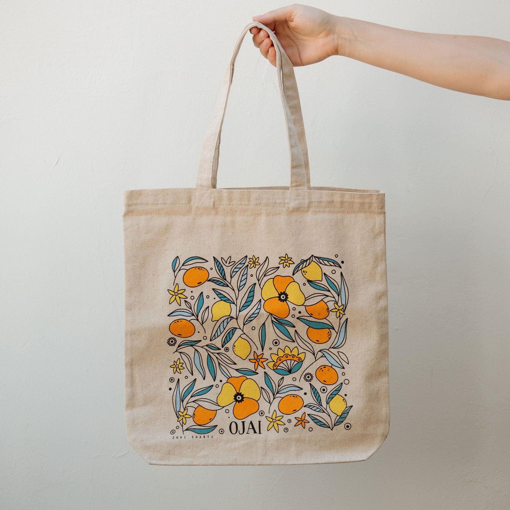 arm holding a colorful citrus tote against a neutral background