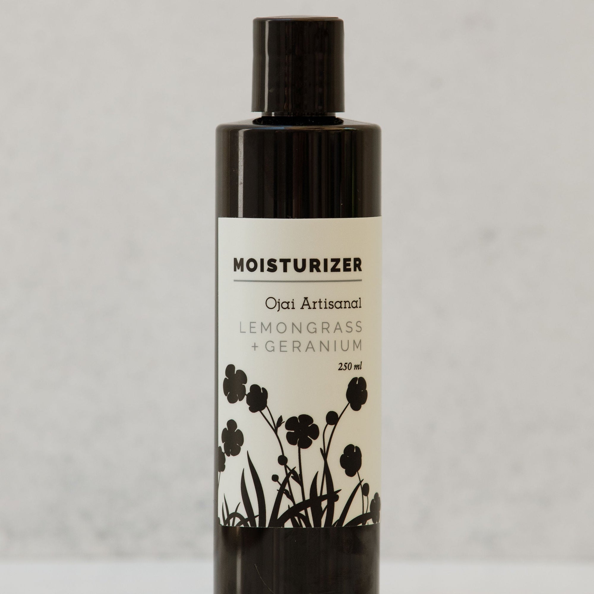 Moisturizer bottle with lemongrass and geranium label on a light gray background