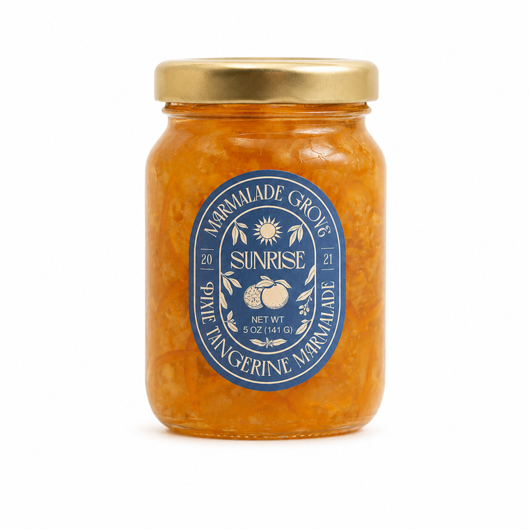 A glass jar of Sunrise Pixie Tangerine Marmalade by Marmalade Grove, filled with orange marmalade and topped with a gold metal lid, set against a plain white background