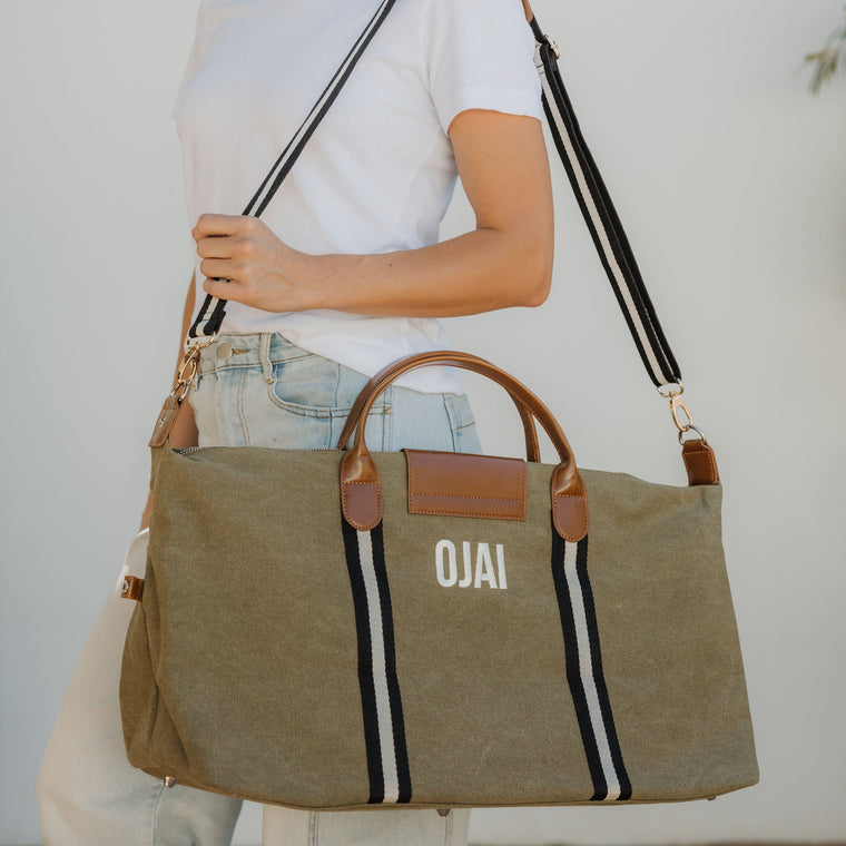 Person holding a green bag with 'OJAI' branding against a neutral background