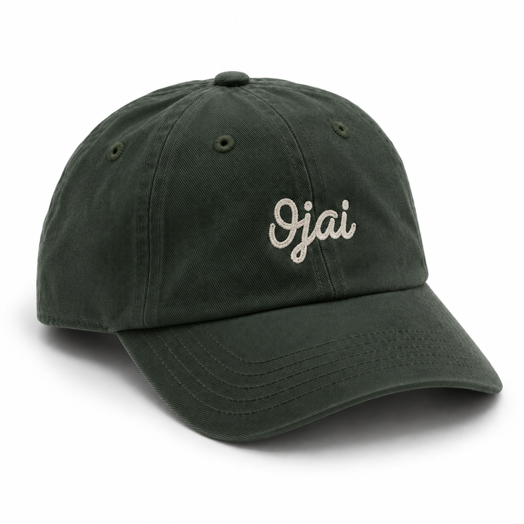 A dark forest green cotton baseball cap with 'Ojai' embroidered in white cursive script on the front, shown on a clean white background.