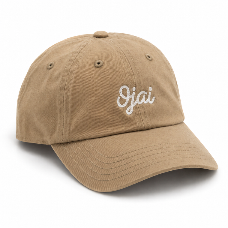 A tan cotton baseball cap with 'Ojai' embroidered in white script on the front, shown on a clean white background.