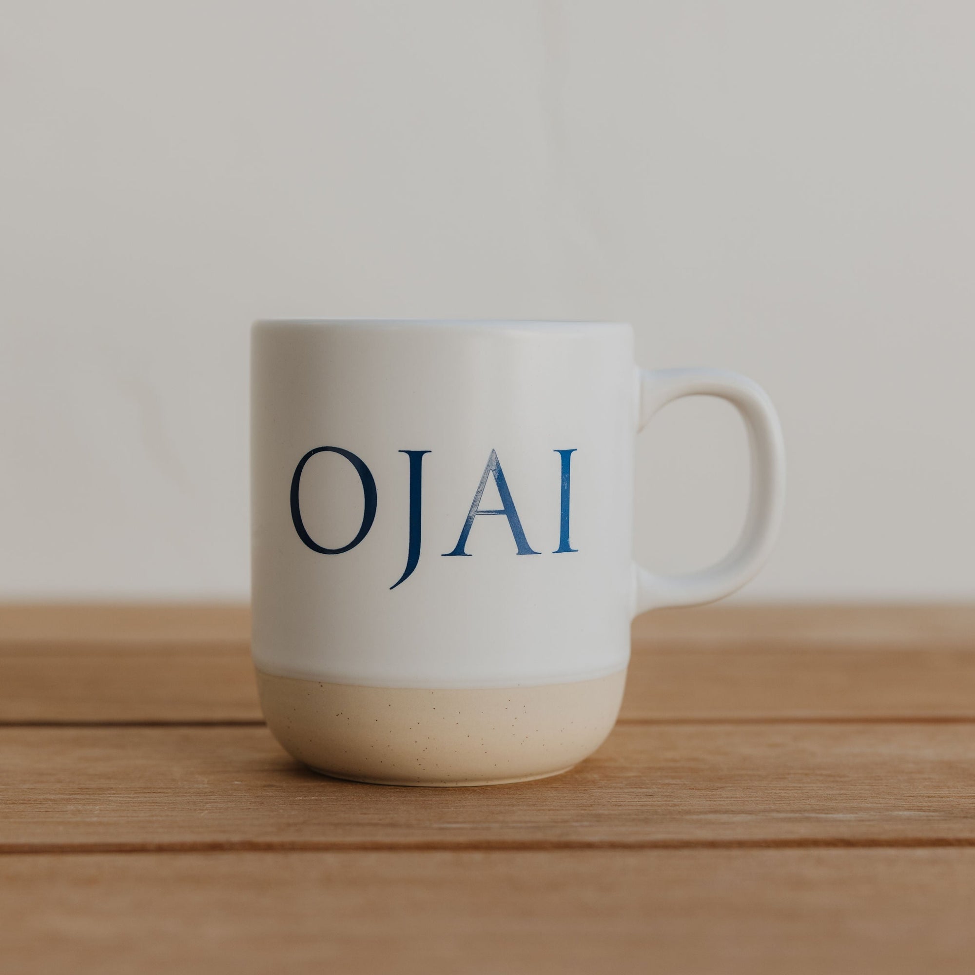 White mug with 'OJAI' text on a wooden surface