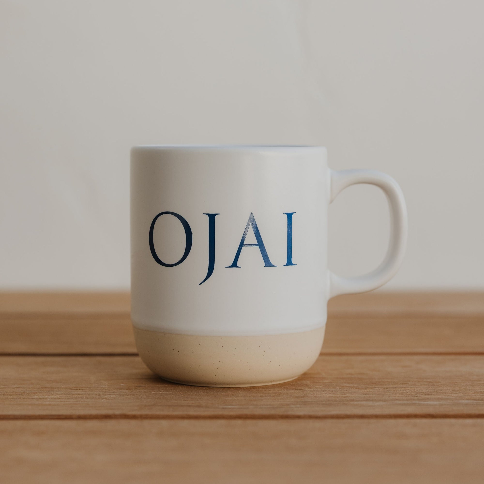 White mug with 'OJAI' text on a wooden surface