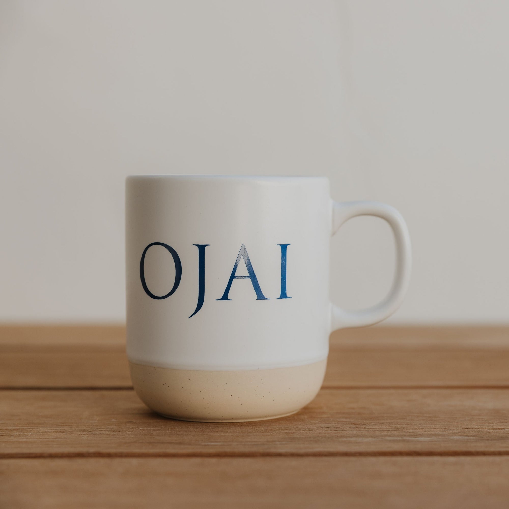 White mug with 'OJAI' text on a wooden surface