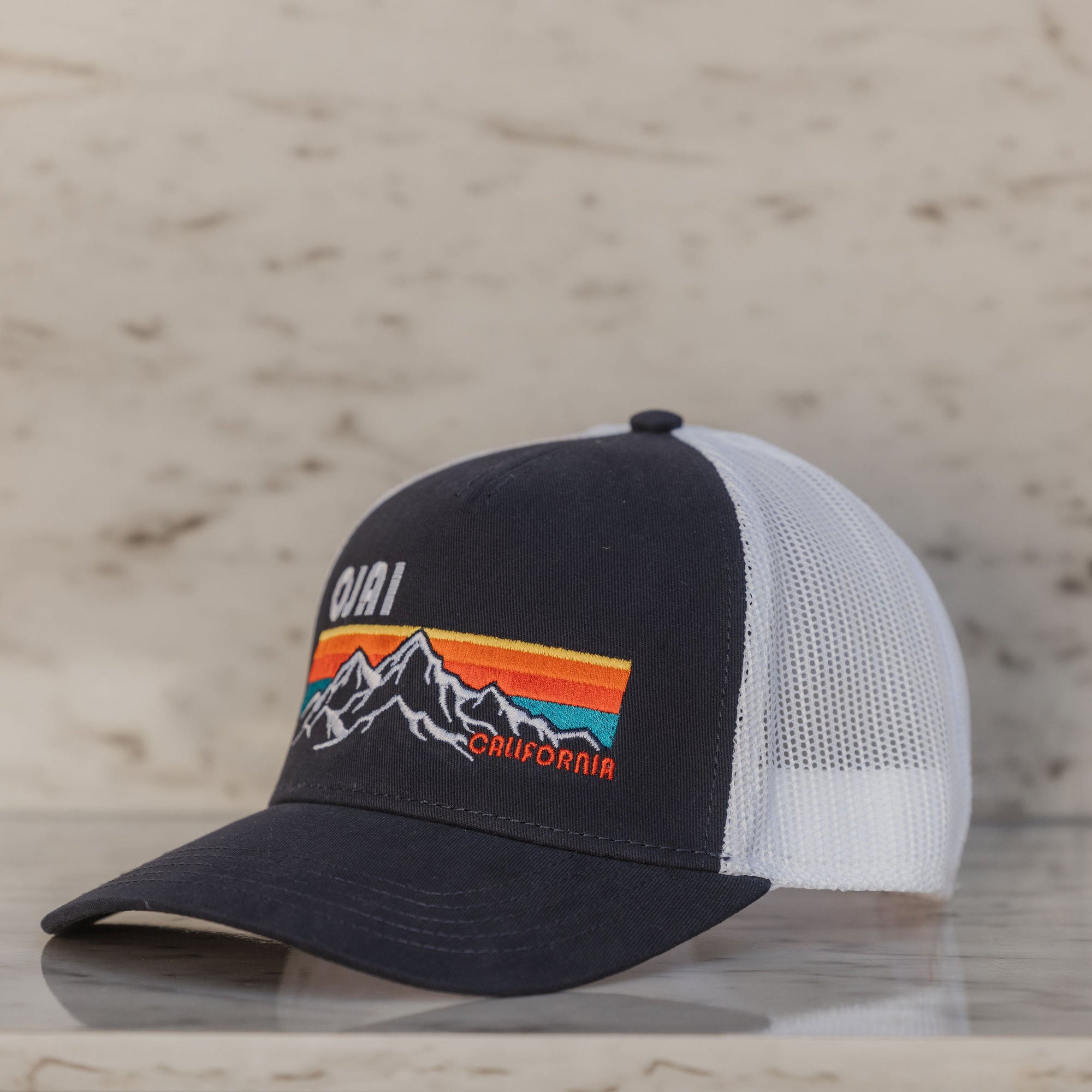 Black and white cap with mountain design on a wooden surface