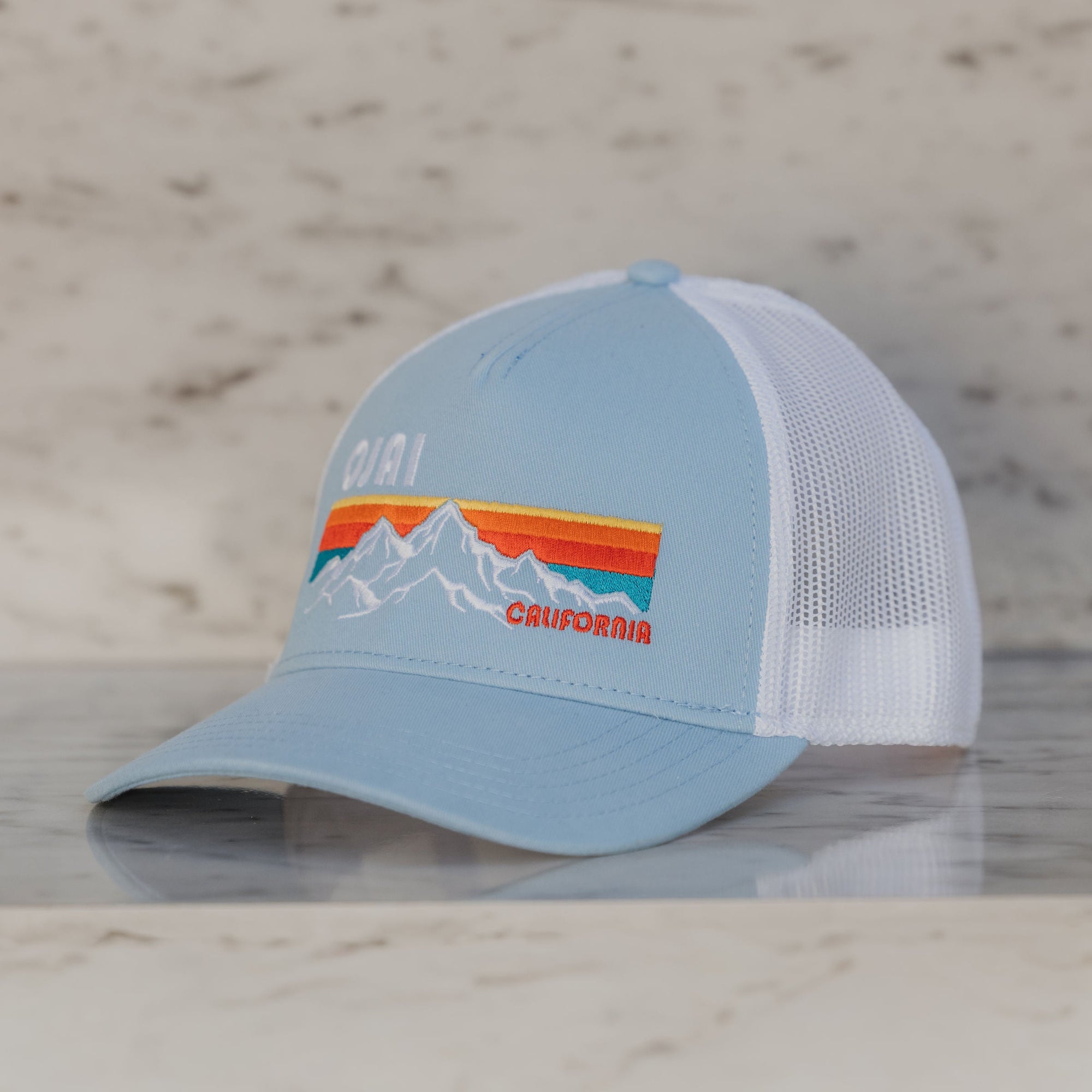 Light blue cap with mountain design on a marble surface