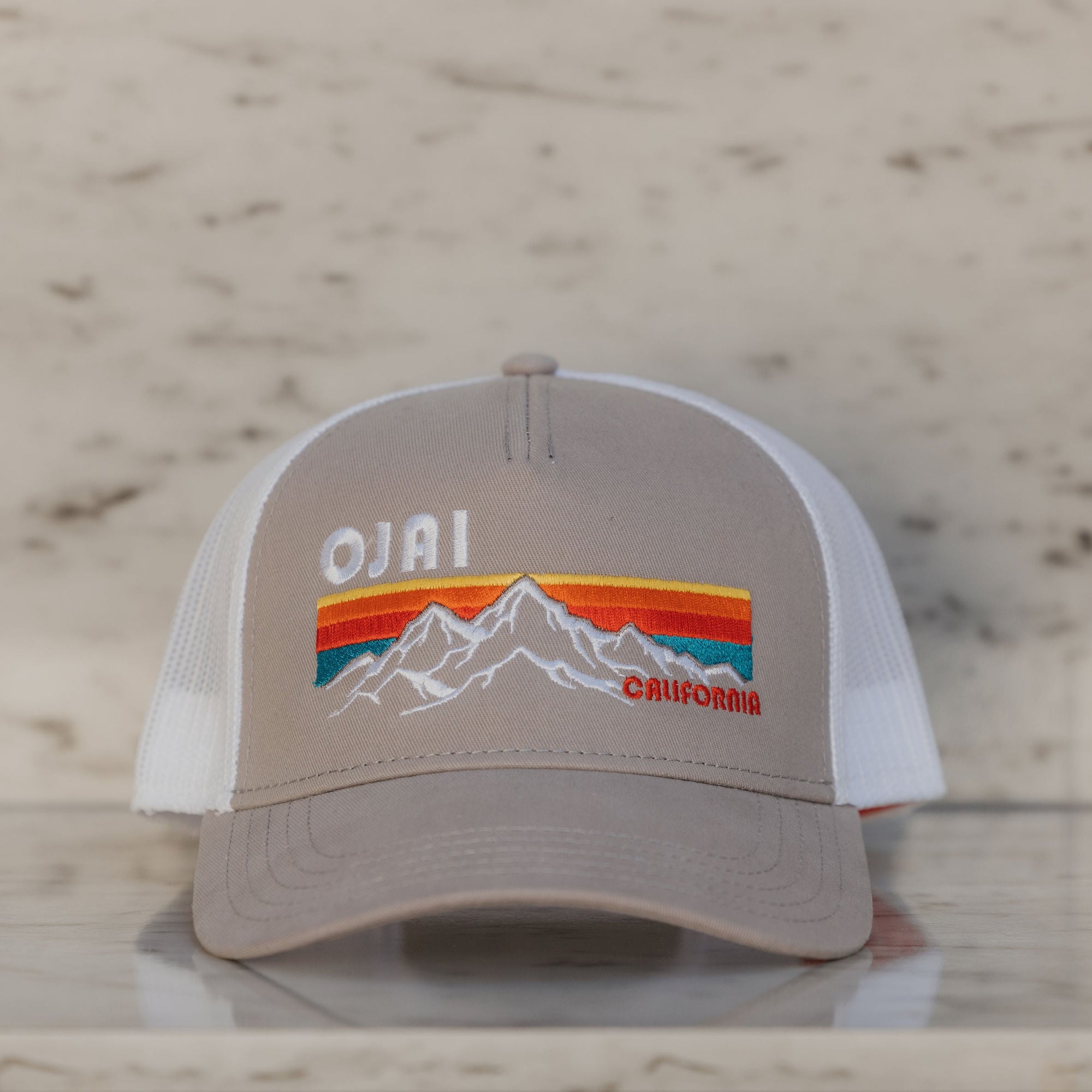 Trucker hat with 'Ojai California' design on a marble surface