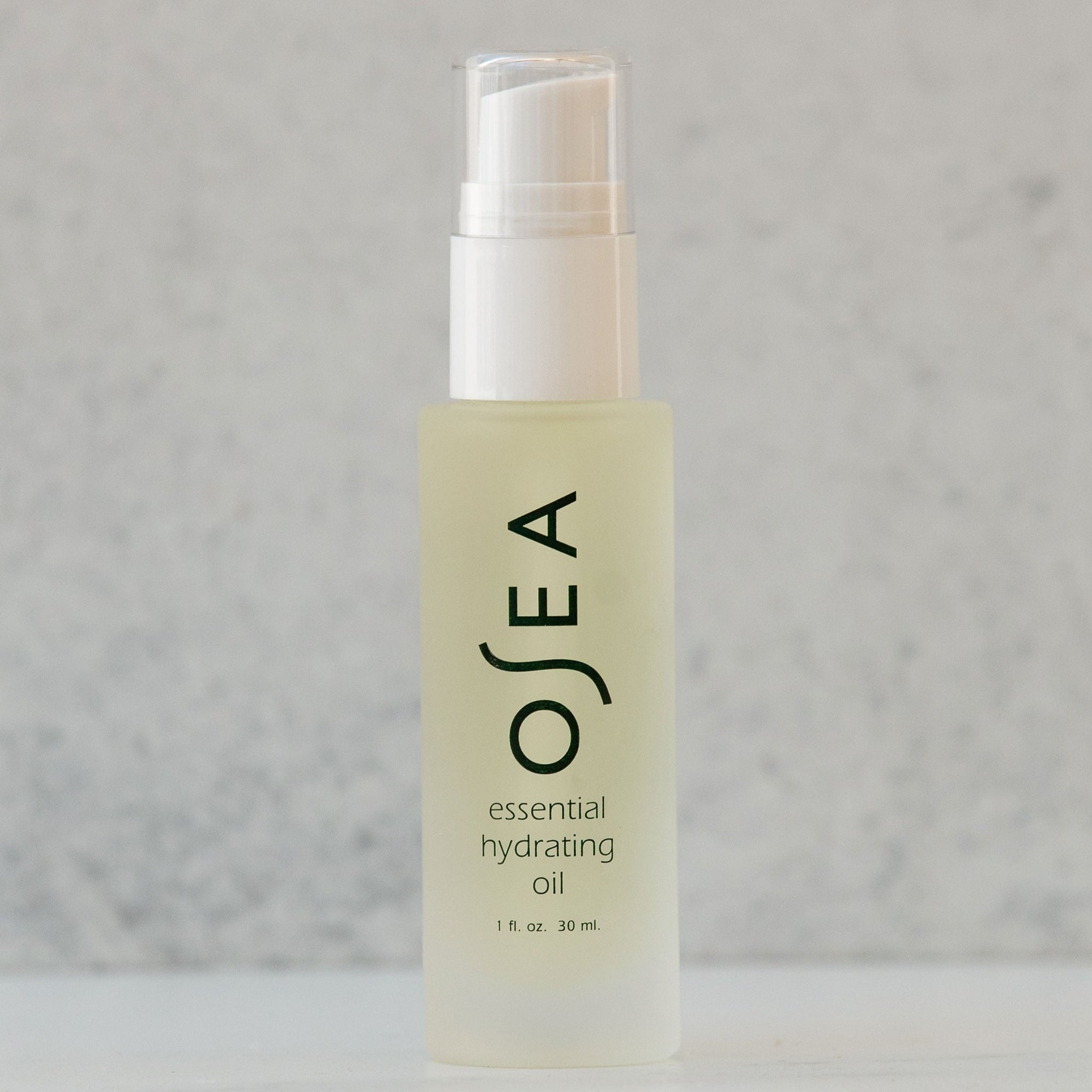A clear bottle containing OSEA Essential Hydrating Oil with a white cap, displayed against a light grey background.