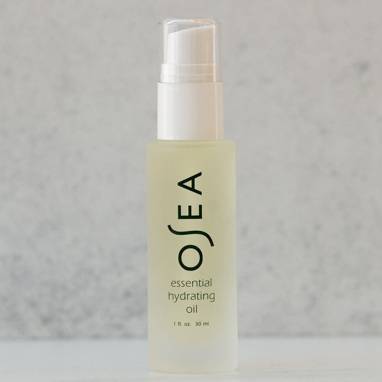 A clear bottle containing OSEA Essential Hydrating Oil with a white cap, displayed against a light grey background.