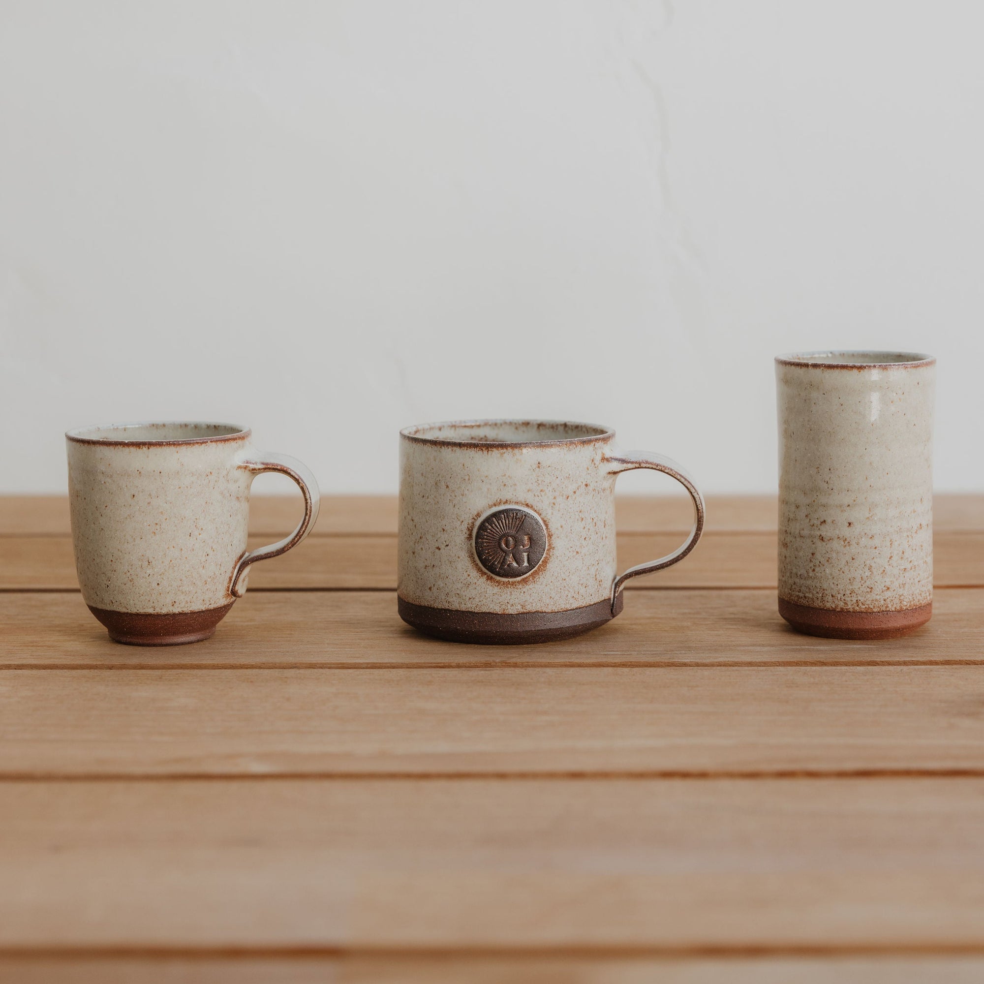 Three ceramic mugs on a wooden surface with a plain background