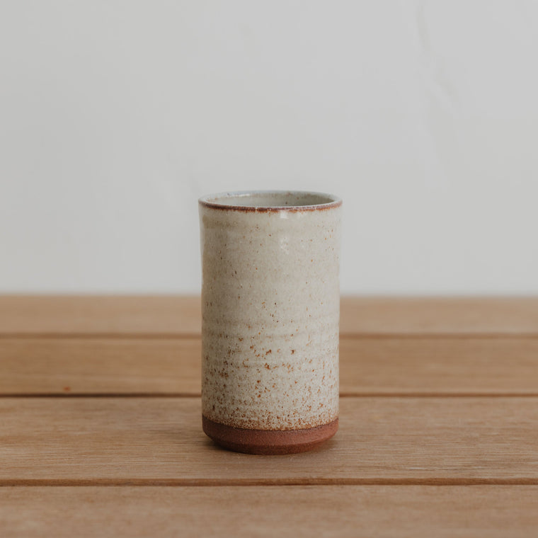 two toned ceramic tumbler set on table against a neutral background