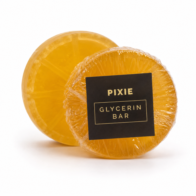 Two round yellow-orange glycerin bars wrapped in clear plastic, with one bar in front featuring a black square label that reads 'PIXIE GLYCERIN BAR' in gold lettering, on a white background.