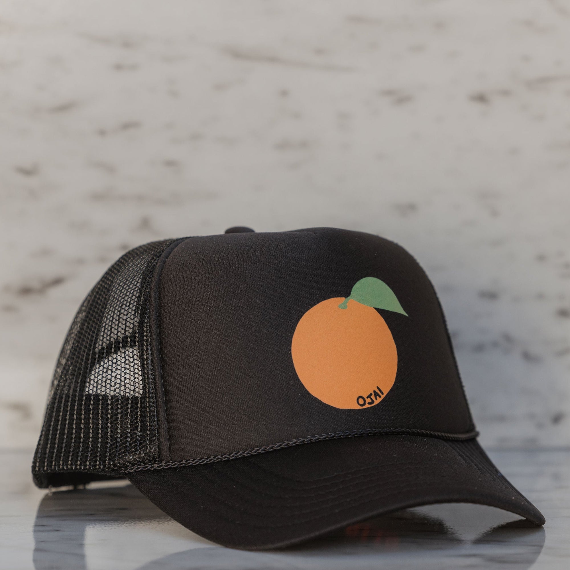 Black cap with a peach logo on a marble surface