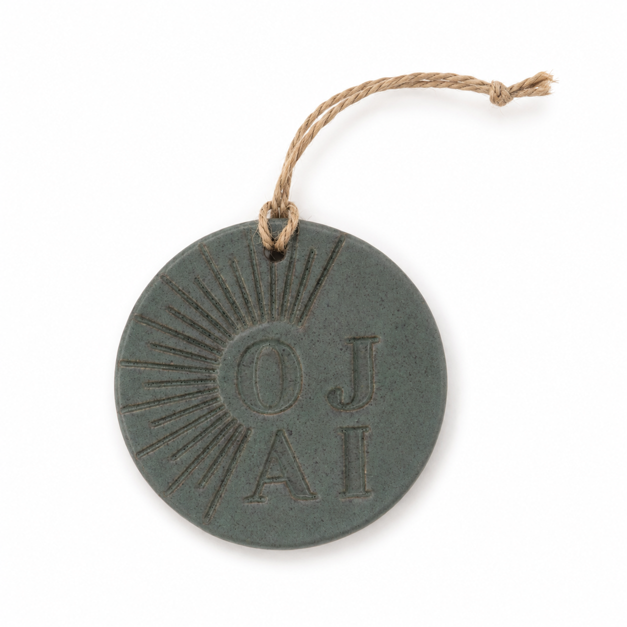 A round dark gray ceramic ornament with a hanging twine string, featuring the embossed initials 'OJA' and a sunburst design, shown on a white background.