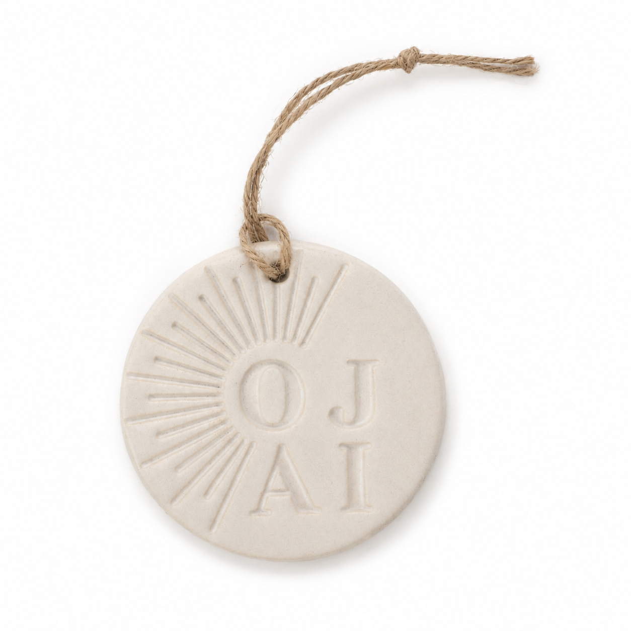 A round, off-white ceramic or stone wall hanging ornament with a natural jute hanging string. The ornament features an embossed sunburst design and the initials 'OJA' in a serif font.