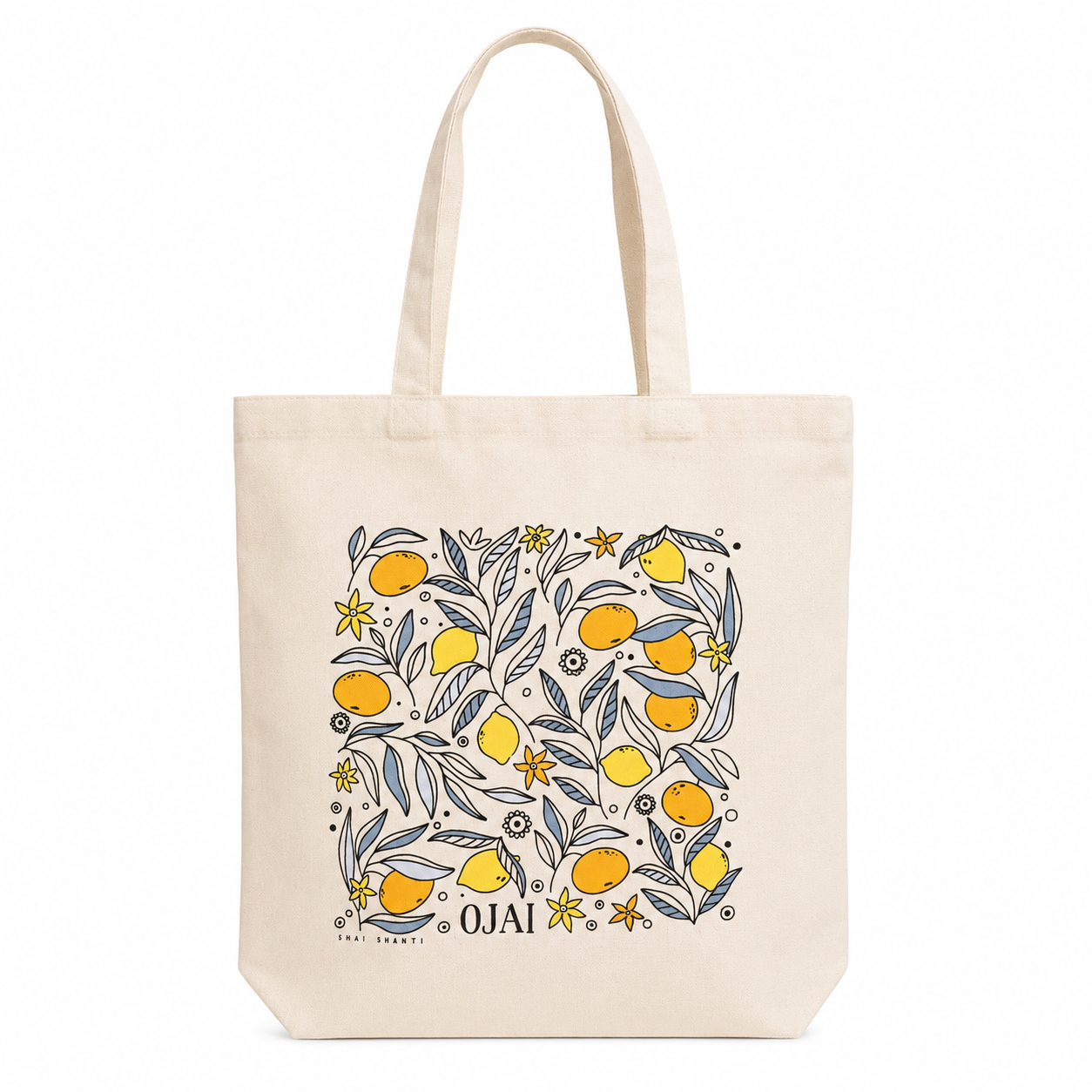 A cream-colored canvas tote bag with a square graphic print featuring yellow oranges, blue-gray leaves, and yellow flowers, with the brand name 'OJAI' printed at the bottom.