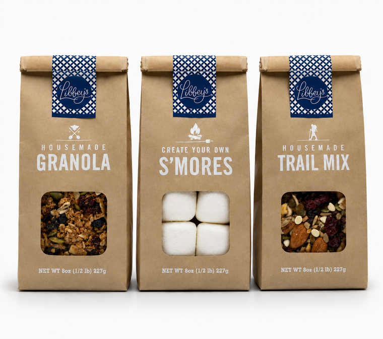 Three kraft paper bags of Libby's housemade granola mixes displayed side-by-side on a white background. The bags feature blue patterned bands with the Libby's logo and display clear windows showing the contents: a granola mix, white marshmallows for s'mores, and a trail mix.