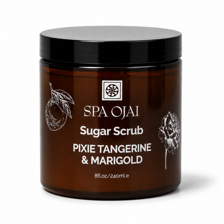A dark amber glass jar of SPA OJAI Sugar Scrub with a black lid, labeled 'PIXIE TANGERINE & MARIGOLD', on a white background.