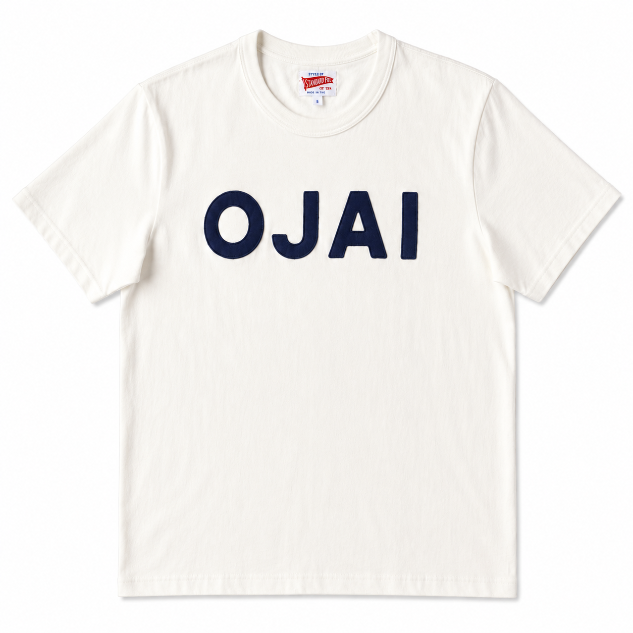 An off-white crewneck t-shirt featuring the word 'OJAI' printed across the chest in bold navy blue block letters, displayed flat against a clean white background.