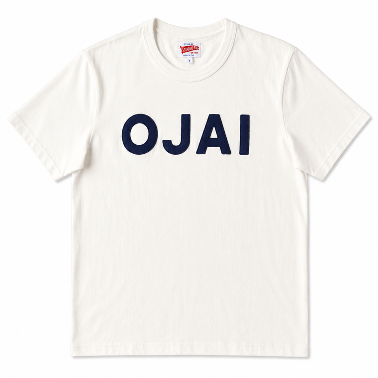 An off-white crewneck t-shirt featuring the word 'OJAI' printed across the chest in bold navy blue block letters, displayed flat against a clean white background.