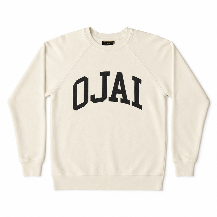 An off-white crewneck sweatshirt with 'OJAI' printed in black arched varsity letters across the chest, displayed flat against a white background.