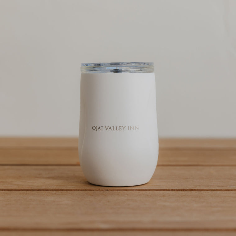 White tumbler with 'Ojai Valley Inn' text on a wooden surface
